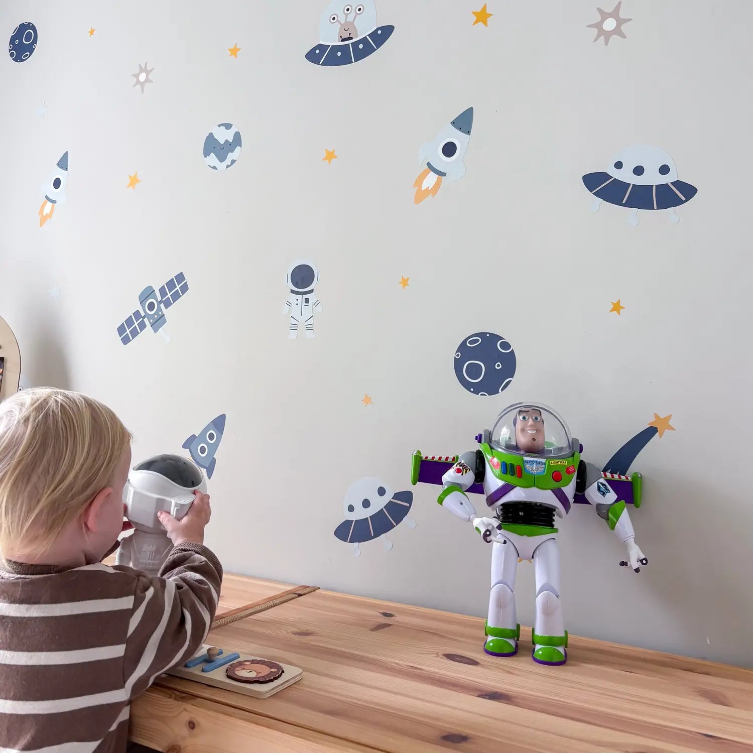 Child playing with space-themed wall decals including rockets, planets and astronauts