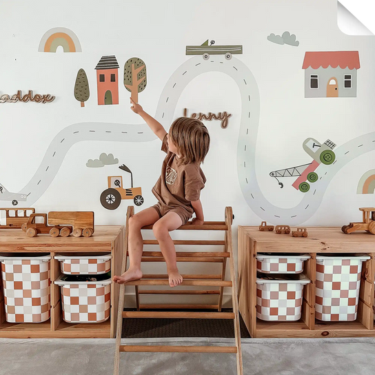 A child in a brown outfit sitting on a wooden climbing toy.