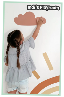 Child applying a wall decal of a cloud and rainbow.