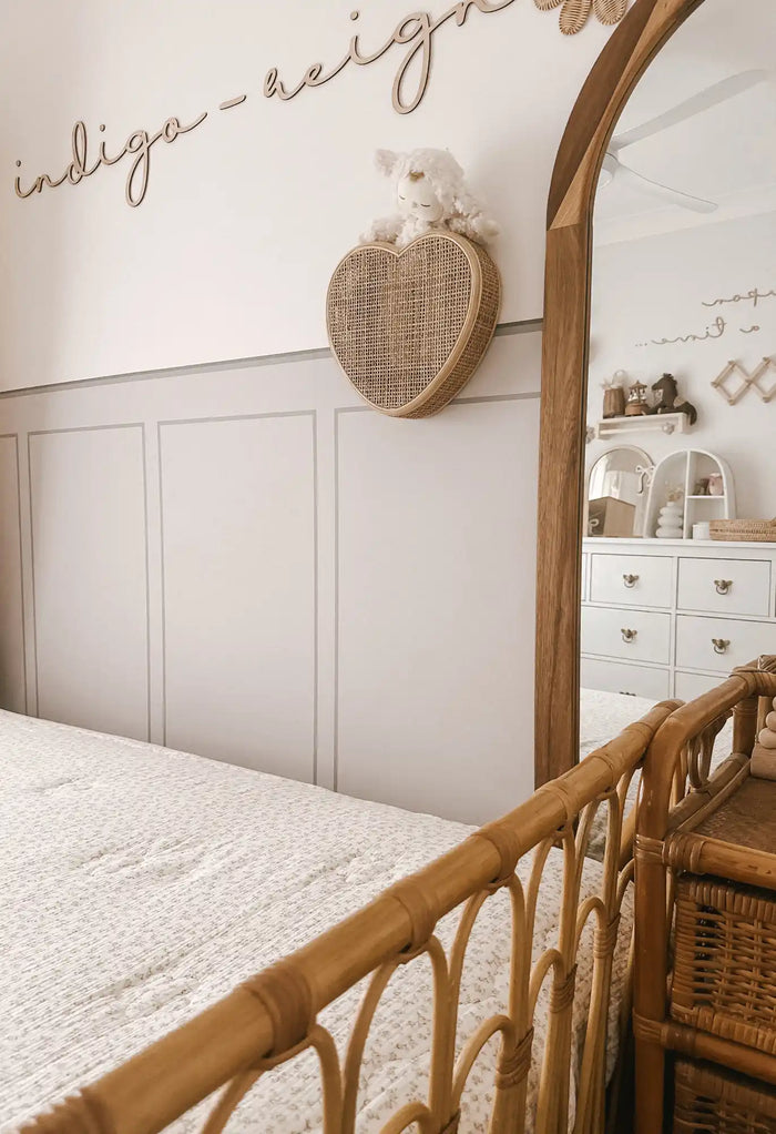 Rattan baby crib with arched detailing.
