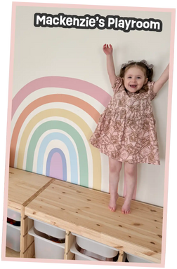 A smiling young girl in a pink patterned dress.